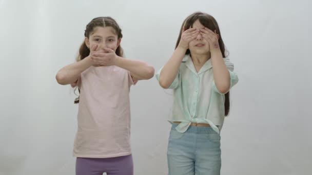 Dwie Małe Dziewczynki Białym Tle Zakrywają Usta Oczy Dziewczynki Jedna — Wideo stockowe