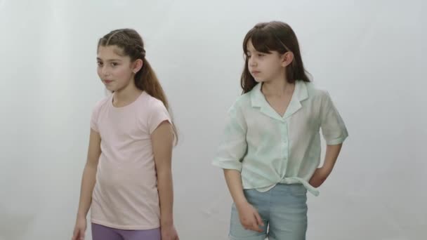 白を背景に二人の女の子がお互いの横に立って孤立した 警告をジェスチャーするカジュアルTシャツやジーンズで精力的な女の子 いいえ 注意してください スコアリングと不承認を示す — ストック動画