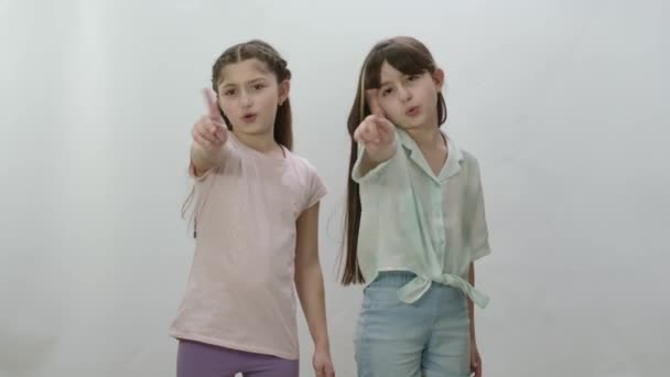 白を背景に二人の女の子がお互いの横に立って孤立した 警告をジェスチャーするカジュアルTシャツやジーンズで精力的な女の子 いいえ 注意してください スコアリングと不承認を示す — ストック動画