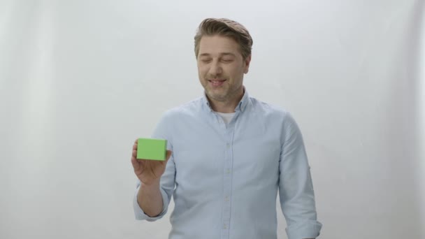 白い背景に孤立した若い男のスタジオの肖像画 緑色の箱を持っている人はプロダクトが優れている示す クリエイティブ3Dアーティストは 緑のボックスを任意の製品に置き換えることができます — ストック動画