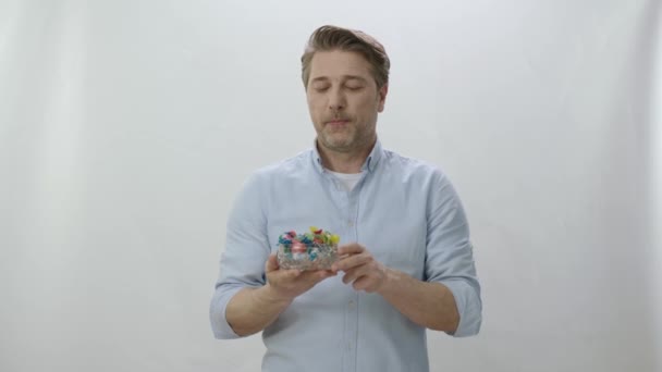 Beyaz Arka Plandaki Adam Farklı Lolipopları Şekerlemeleri Kaseden Kameraya Veriyor — Stok video