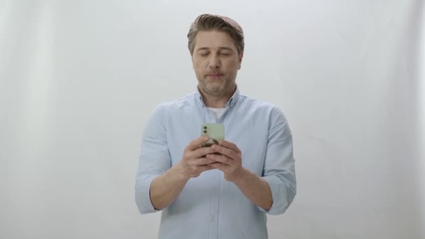 Mladý Muž Tráví Čas Internetu Chytrým Telefonem Bílém Pozadí Šťastný — Stock video