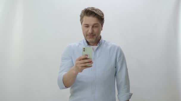 Young Man Spends Time Internet His Smartphone Phone White Background — Stock Video