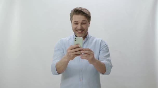 Мужчина Делает Видеозвонок Телефону Белом Фоне Счастливый Мужчина Голубой Рубашке — стоковое видео