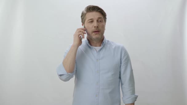 若い男は携帯電話の呼び出しに満足している 肖像画ハンサムな男 白い背景に隔離された電話をかける ビジネスマンがスマホで話してる — ストック動画