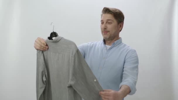 Молодой Человек Изолированный Белом Фоне Проверяет Свою Свежевымытую Рубашку Наличие — стоковое видео