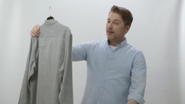 Unge Man Isolerad Vit Bakgrund Kollar Sin Nytvättade Skjorta Efter — Stockvideo