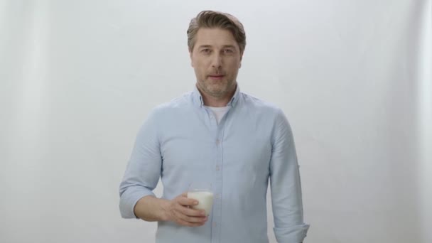 白い背景にミルクのガラスの若い男 カルシウムの力 白地にスクリーンの左側の架空の人物と話す男 — ストック動画