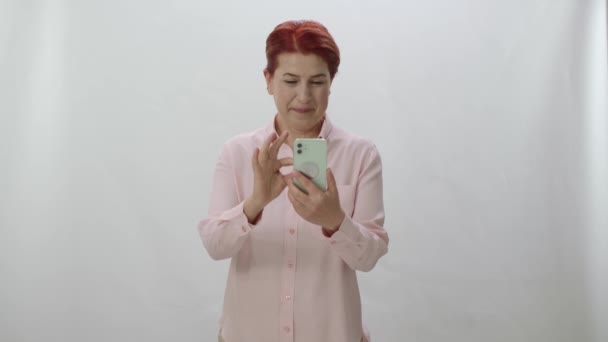 Жінка Рудим Волоссям Проводить Час Інтернеті Своїм Смартфоном Білому Фоні — стокове відео