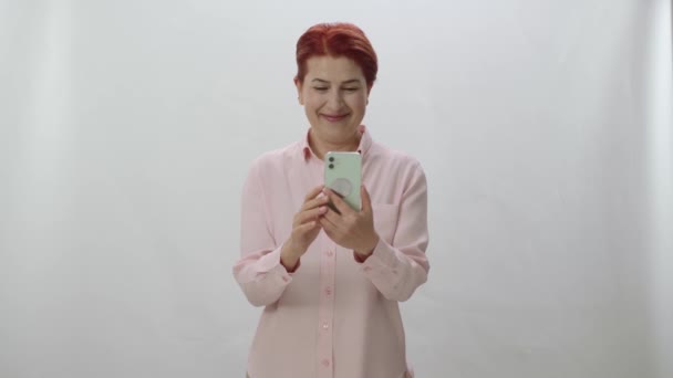 Červenovlasá Žena Tráví Čas Internetu Svým Smartphonem Bílém Pozadí Žena — Stock video