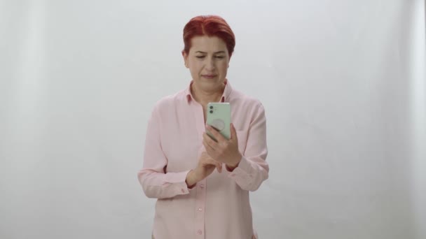 Жінка Рудим Волоссям Проводить Час Інтернеті Своїм Смартфоном Білому Фоні — стокове відео