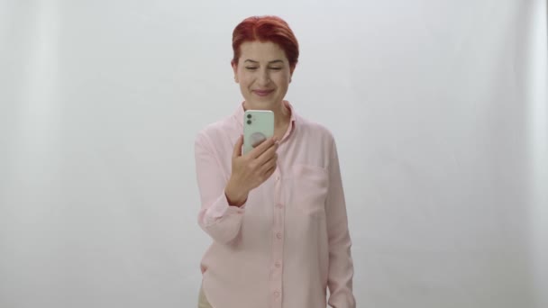 Roodharige Vrouw Kijkt Naar Groene Scherm Smartphone Witte Achtergrond Met — Stockvideo