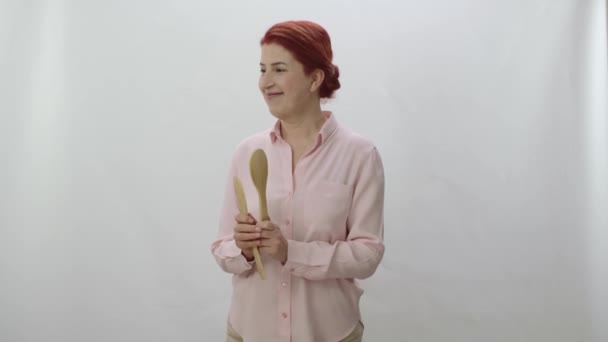 一个女人拿着木制勺子对着屏幕的一角说话 问问题 对答案感到惊讶 有创意的人可以把他们想要的东西放在女人想看的地方 — 图库视频影像