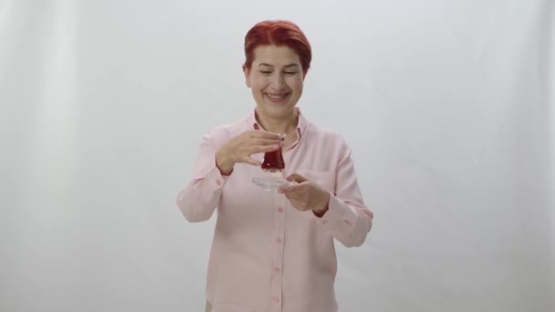 伝統的なガラスのカップで黒や緑のお茶を飲むのが好きな赤毛の女性の文字の肖像画 健康的な女性は ガラスカップでお茶の匂い お茶の色を見て それを飲む — ストック動画