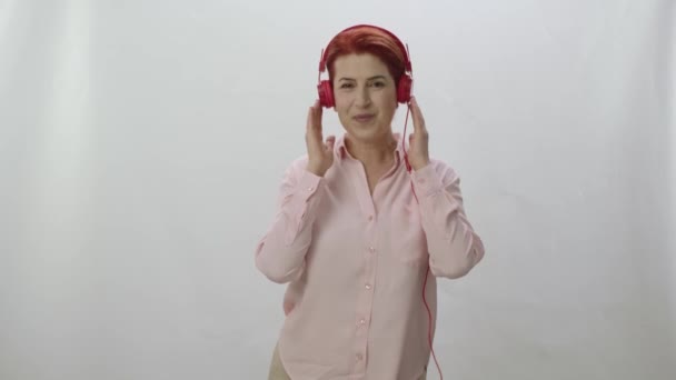 带着耳机唱歌的女人被白色背景隔离了女人用红色耳机跳舞和听音乐 恋爱中的女人的画像 — 图库视频影像