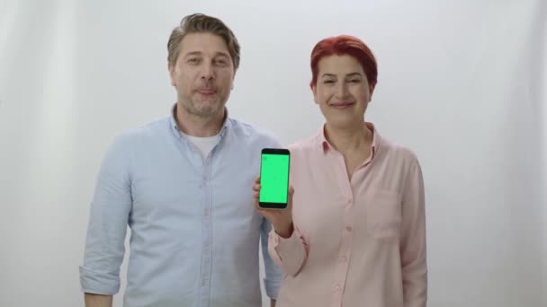 Casal Está Segurando Smartphone Com Uma Tela Verde Fundo Branco — Vídeo de Stock