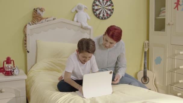 View Cheerful Mother Sitting Bed Little Son Playing Games Tablet — Stock Video