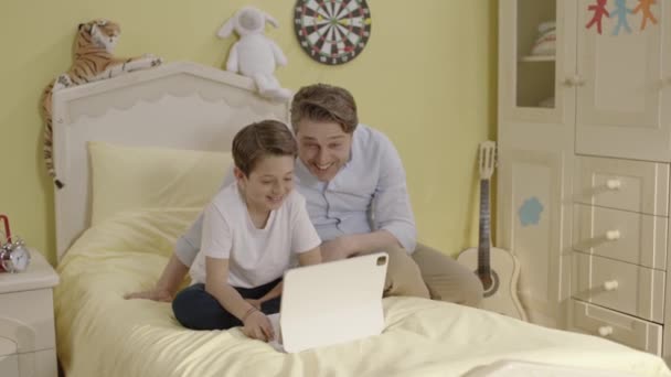 Zicht Vrolijke Vader Zitten Bed Met Kleine Zoon Spelen Games — Stockvideo