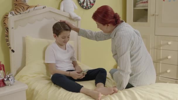Matka Sedí Posteli Malým Synem Pomocí Smartphonu Chlapec Pokračuje Hrát — Stock video