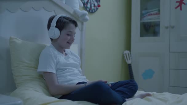 Мальчик Слушает Музыку Смартфоном Наушниками Постели Child Listens Audiobooks Smartphone — стоковое видео