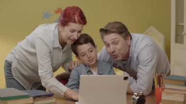 Mutlu gülümseyen ebeveynler çocuklarının odasında tablet bilgisayarla vakit geçiriyorlar. Mutlu aile çocuk odasında komik videolar izliyor. Mutlu ebeveynler evdeki tablet bilgisayardan komik videolar saklıyor..