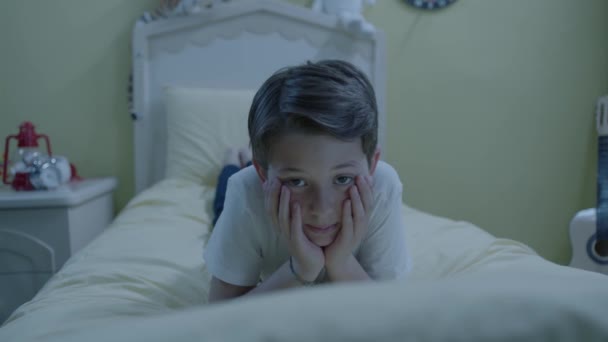 次の日の興奮のために 彼の頬に彼の手でベッドの上の彼のパジャマに横たわっている不幸な子供は眠ることができません — ストック動画