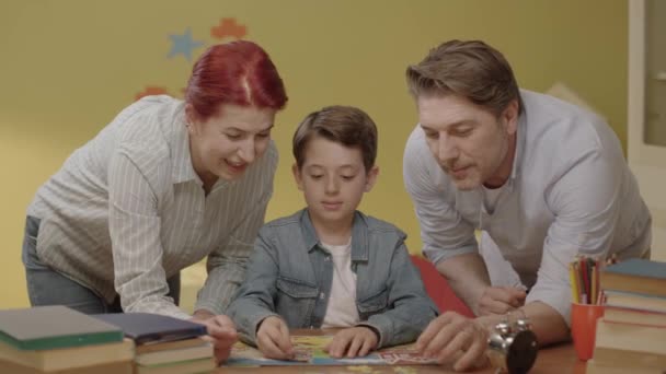 Kleine Jongen Die Legpuzzels Doet Met Ouders Aan Zijn Tafel — Stockvideo