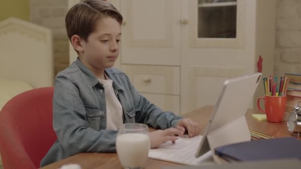 Menino Está Bebendo Leite Enquanto Faz Suas Lições Computador Tablet — Vídeo de Stock