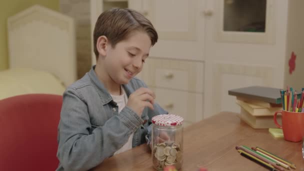 Ailesinden Para Biriktirmeyi Öğrenen Küçük Çocuk Evdeki Masasının Üzerindeki Kumbarasına — Stok video