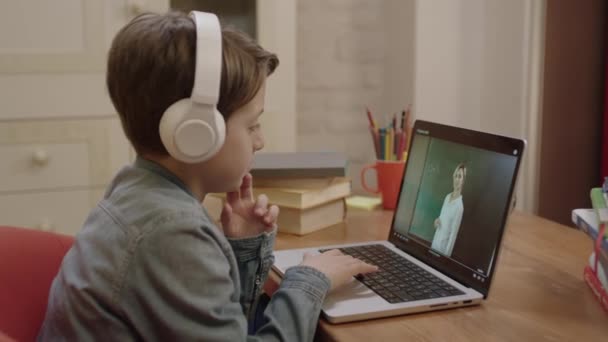 Маленький Школяр Вивчає Онлайн Дому Використовуючи Навушники Ноутбуці Слухаючи Вчителів — стокове відео