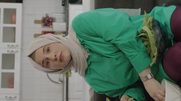 年轻女人在看电视的时候戴头巾剪绿豆 女性准备食物的肖像 垂直故事录像 — 图库视频影像