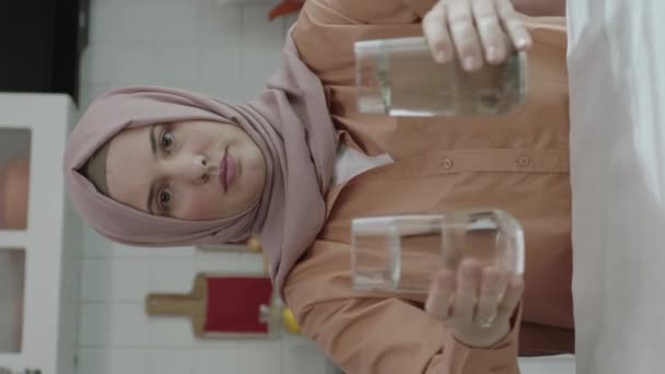 イスラム教徒のヒジャーブ人は汚れたガラスを片手にヒジャーブの女性に服を着せた 女性は水の汚染によって乱され この問題に注目します — ストック動画