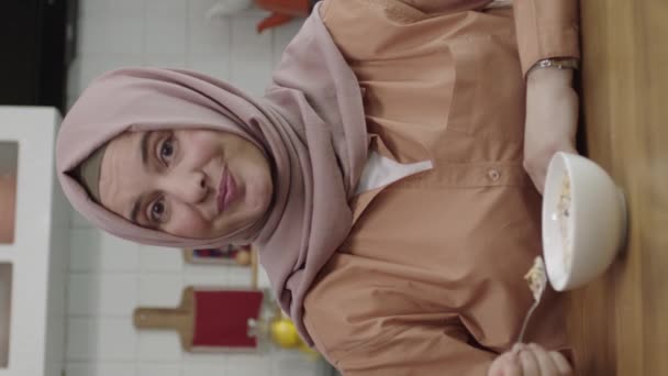 Счастливый Мусульманин Хиджабе Сидящий Дома Кухонным Столом Наливающий Молоко Миску — стоковое видео