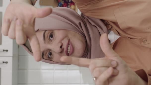 Kobieta Hidżabie Siedzi Kuchni Wykonując Gest Ramki Patrzy Kamerę Oprawia — Wideo stockowe