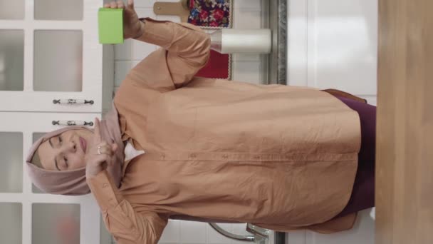 Kobieta Hidżabie Trzyma Coś Zielonego Kuchni Pokazuje Produkt Uśmiecha Się — Wideo stockowe