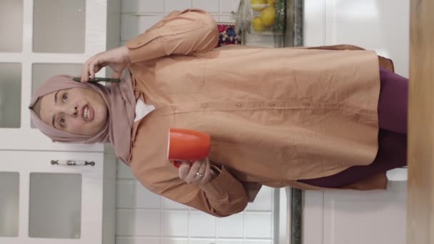 Ung Kvinna Hijab Talar Sin Smartphone Lutar Sig Mot Köksbänk — Stockvideo