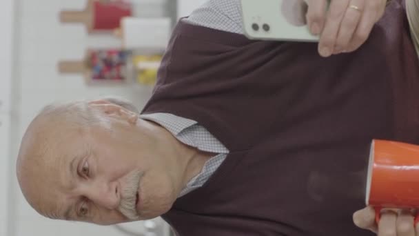Oude Man Kijkt Grappige Video Zijn Smartphone Terwijl Hij Thuis — Stockvideo