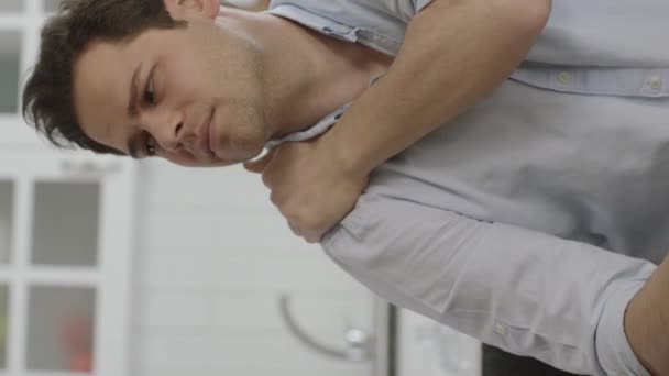 重度の肩 背中や関節の痛みに苦しんで家に座っている若い男は 彼の痛みの部分をマッサージします 仕事のために関節痛を患っている不健康な若者 — ストック動画