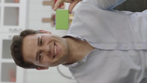 Młody Człowiek Trzymający Coś Zielonego Pokazujący Produkt Uśmiechający Się Prezentujący — Wideo stockowe