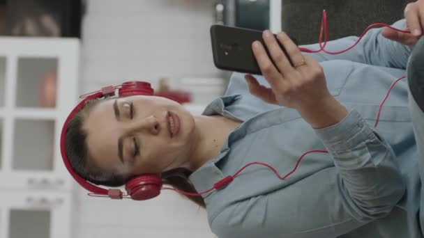 Kanepede Oturan Kadın Evde Müzik Dinlemek Için Kablosuz Kulaklık Kullanıyor — Stok video