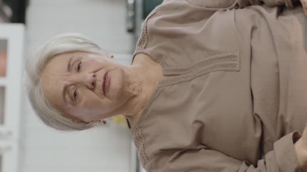 那位老妇人坐在椅子上 肩头和背都痛 她在按摩疼痛的地方 有关节问题的老年妇女的画像 垂直故事录像 — 图库视频影像