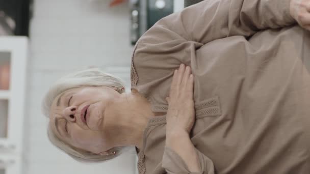 老年妇女坐在家中的扶手椅上 心烦意乱 老年妇女心悸的画像 急性胸痛 心脏病 垂直故事录像 — 图库视频影像