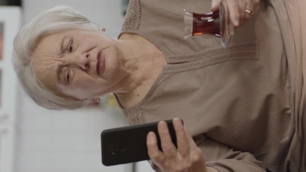 Счастливая Старая Бабушка Держит Мобильный Телефон Видео Звонок Близкими Чашкой — стоковое видео