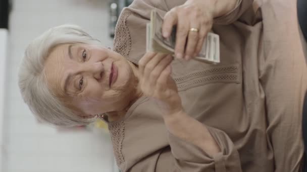 幸せな老婦人は彼女のお金で非常に幸せオンライン宝くじの抽選に勝つ 幸せなシニア女性は多くのドルを保持する 興奮したおばあさんは一人で彼女のドルを楽しんでいます ビデオのために垂直話 — ストック動画