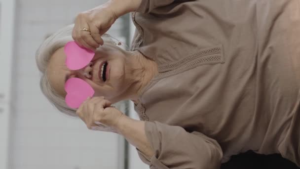 Happy Elderly Woman Holding Two Small Pink Paper Hearts Her — Stock Video