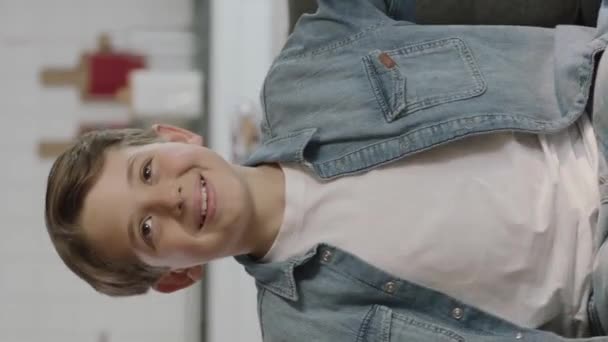 広告スペースを示す少年画面スワイプジェスチャー上の広告スペースで彼の指で自宅のポイントでソファに一人で座っている小さな男の子 垂直ストーリーのためのビデオ — ストック動画