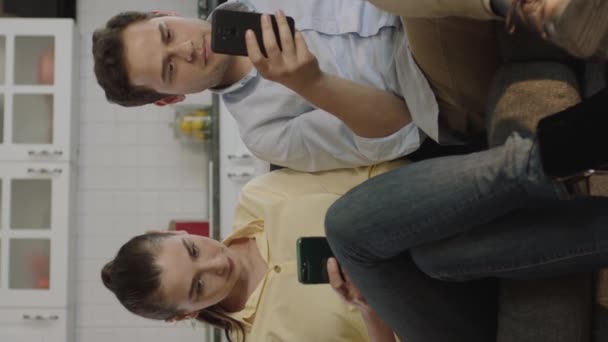 夫妻二人在自家客厅里的手机上查看社交媒体账户 科技成瘾的概念 垂直故事视频 — 图库视频影像