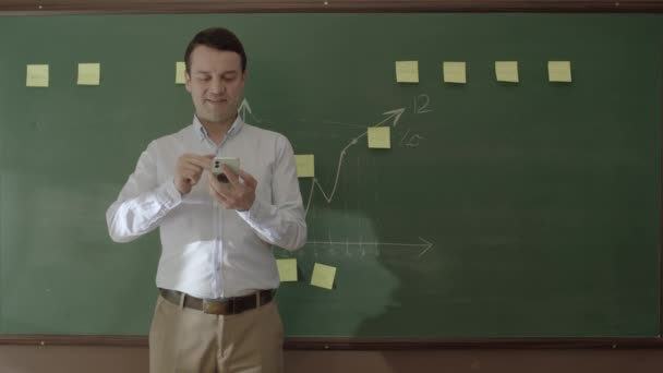 Male Teacher Looking Information Phone Front Blackboard Searching Something Online — Vídeos de Stock