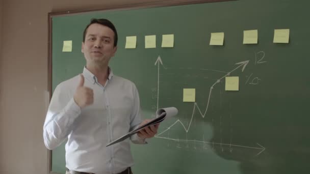 Male Teacher Looks His Notes Front Blackboard Reads Reports His — Vídeos de Stock