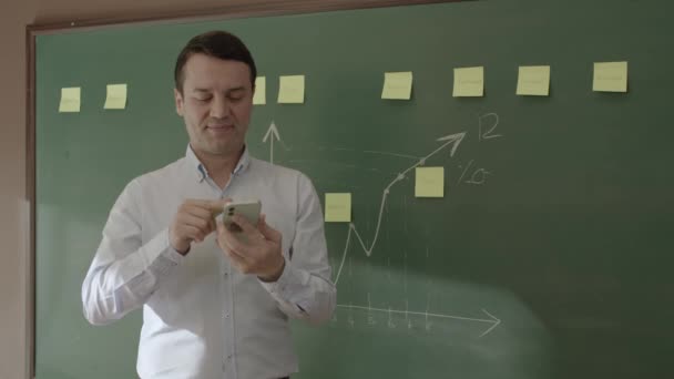 Male Teacher Looking Information Phone Front Blackboard Searching Something Internet — Vídeos de Stock